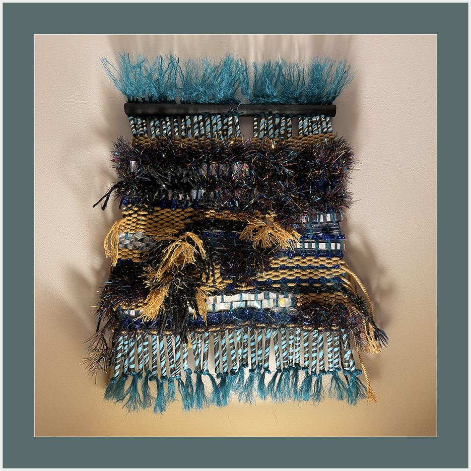 A colorful woven textile artwork incorporating various textures and materials, featuring distinctive patterns and fringes.