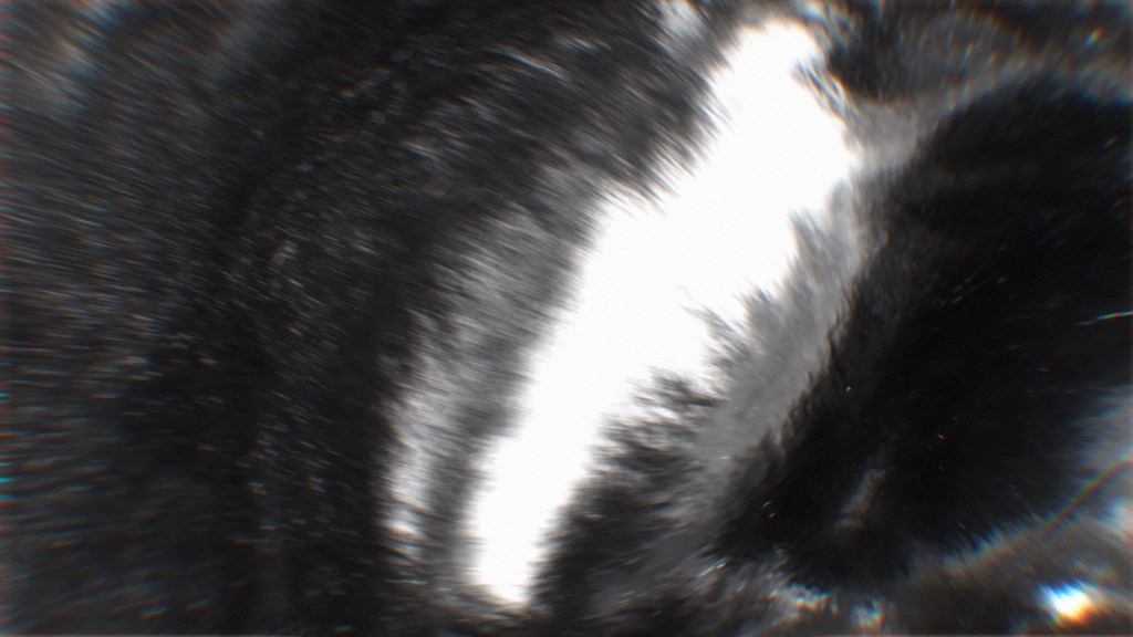 Abstract representation of a swirling dark and light pattern, possibly symbolizing space or cosmic elements. The image evokes a sense of motion and depth.