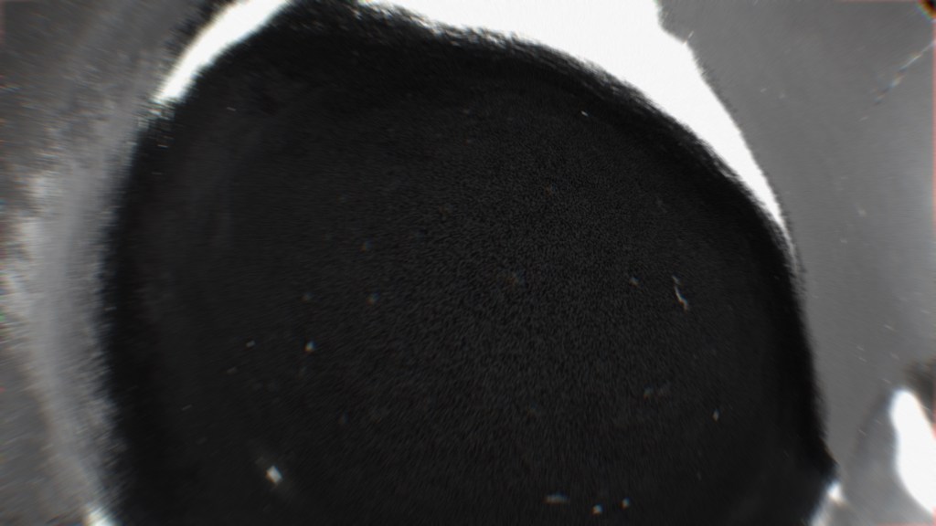 Abstract image featuring a circular shape filled with a dark texture, resembling a cosmic orb or a deep space phenomenon.