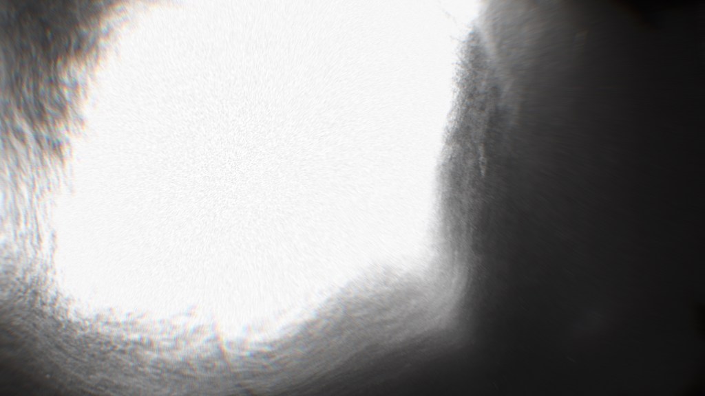 A close-up abstract image showcasing a bright circular light source surrounded by a blurred, dark background, suggesting depth and texture.