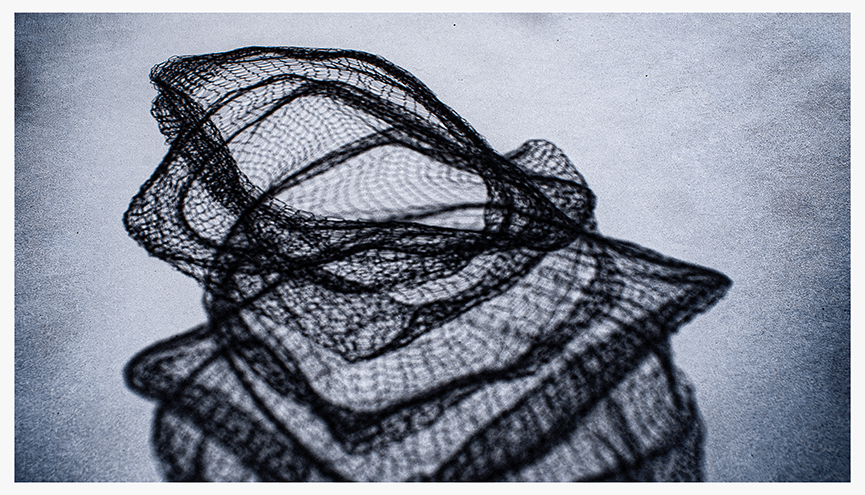 Shadow cast by a delicate, textured black mesh material, creating intricate patterns on a light surface.