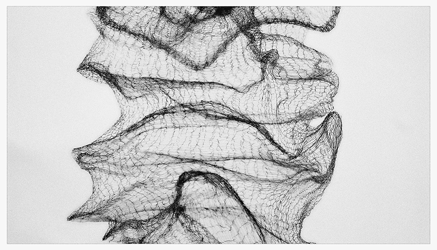 A black and white photograph of delicately arranged copper mesh, showcasing intricate, flowing textures against a plain background.