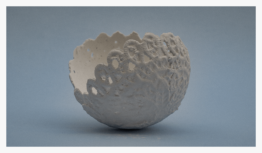 A white, textured bowl resembling a lace doily, positioned against a soft blue background.