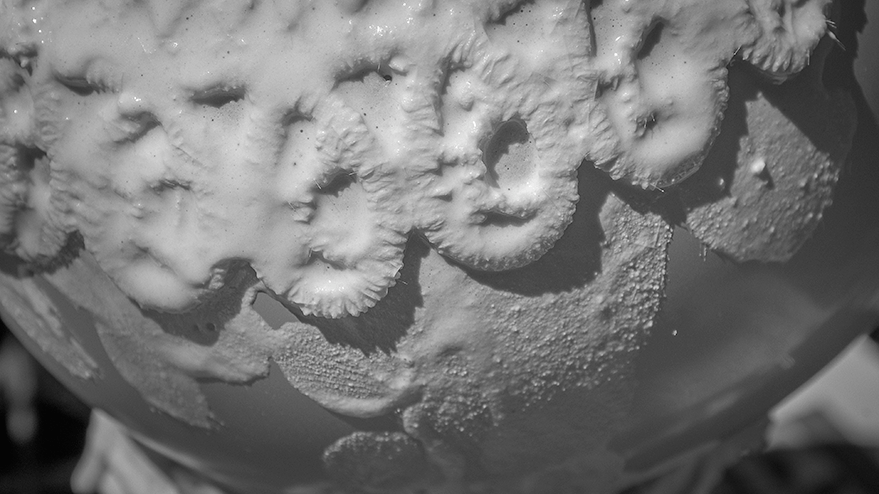 Close-up view of a textured surface resembling lace doilies, coated with a white adhesive material.